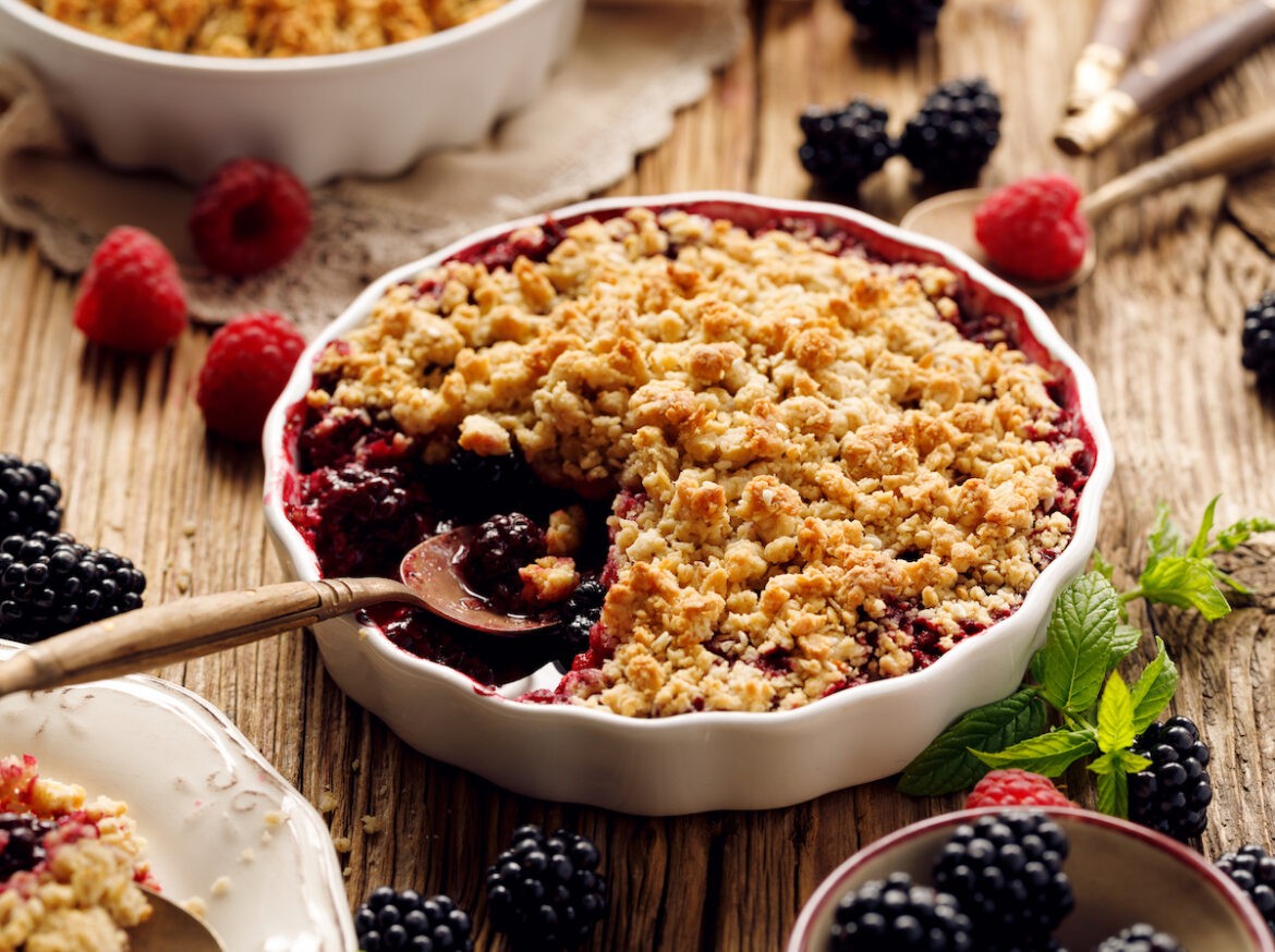 A bowl of berry crumble with a spoon in it.