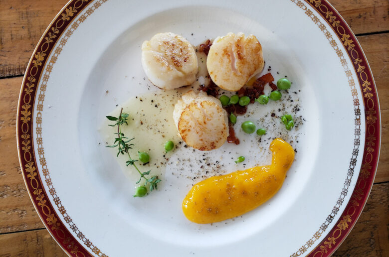 A plate with scallops and mango on it.