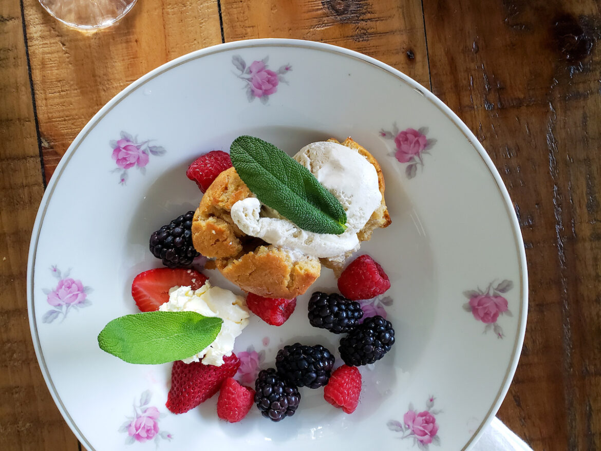 A plate of food with berries and whipped cream.