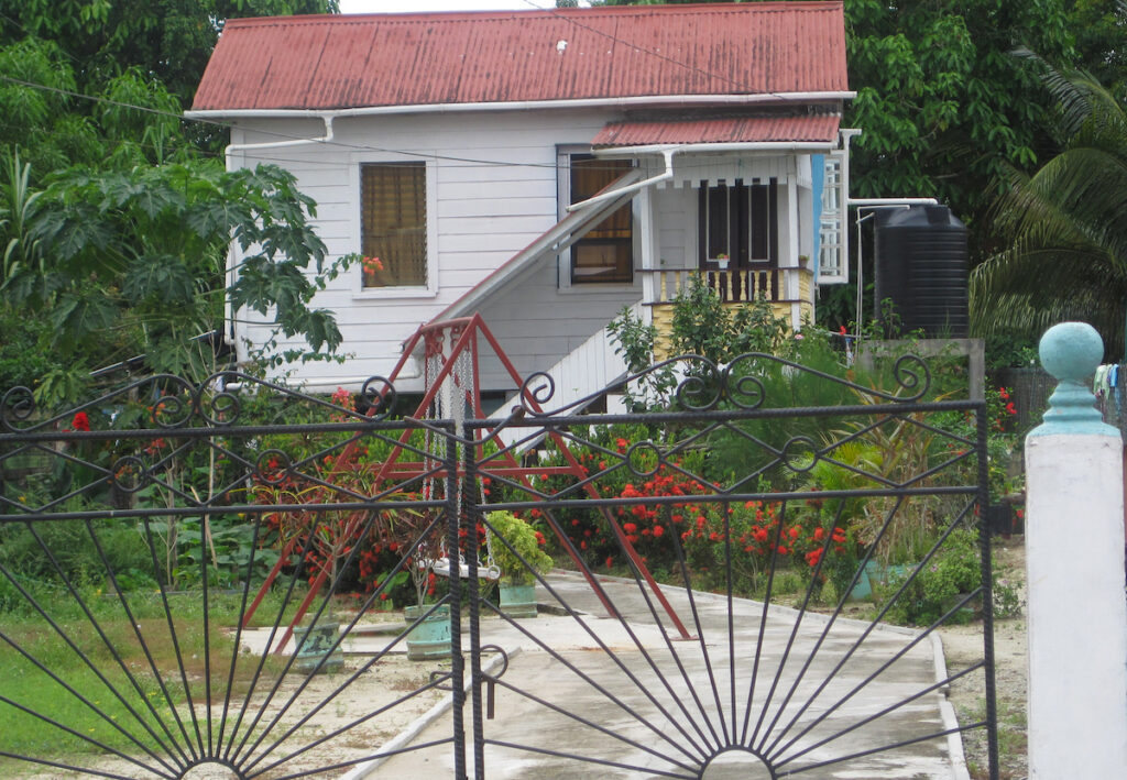 A white house with red roof and metal fence.