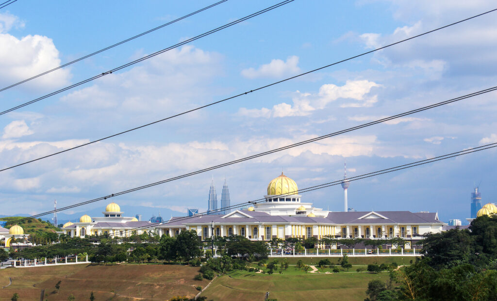 A view of the top of a building with power lines in front.