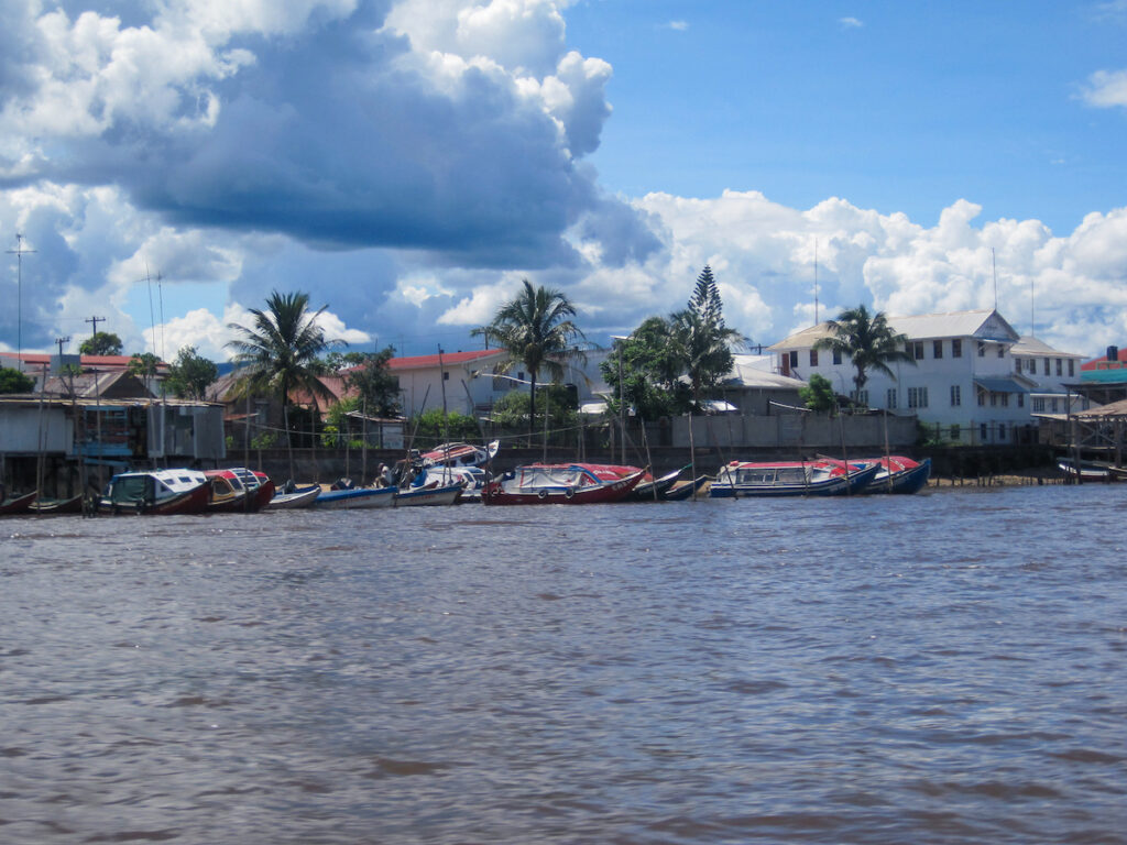 A boat traveling down the river with trees in the background.