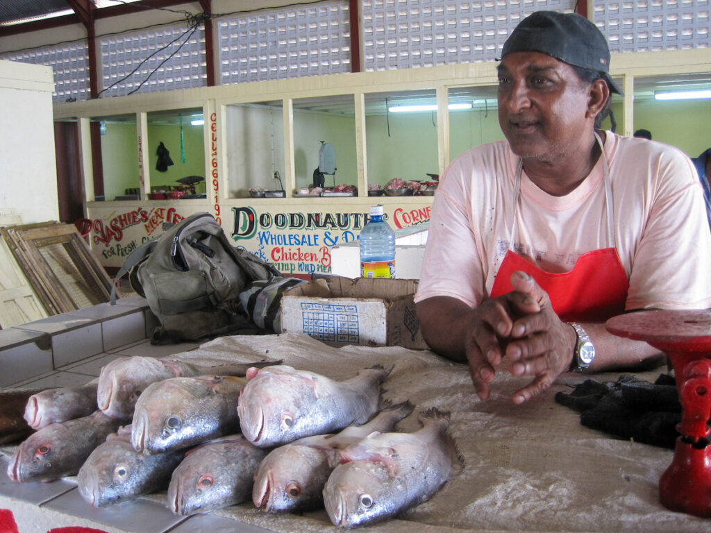 A woman sitting at the counter of a fish market.