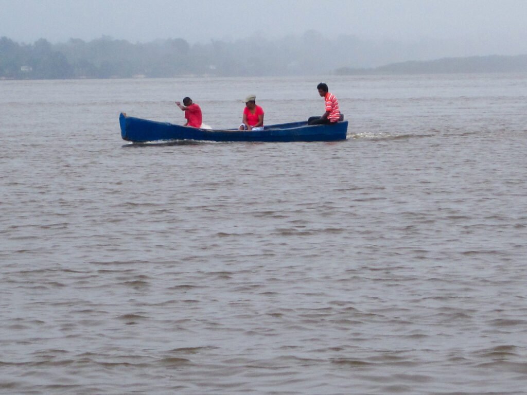 Three people in a blue canoe on the water.