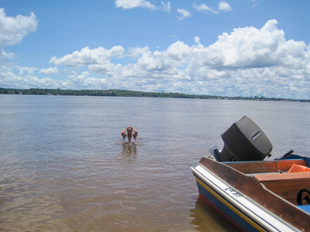 A dog is standing in the water near a boat.