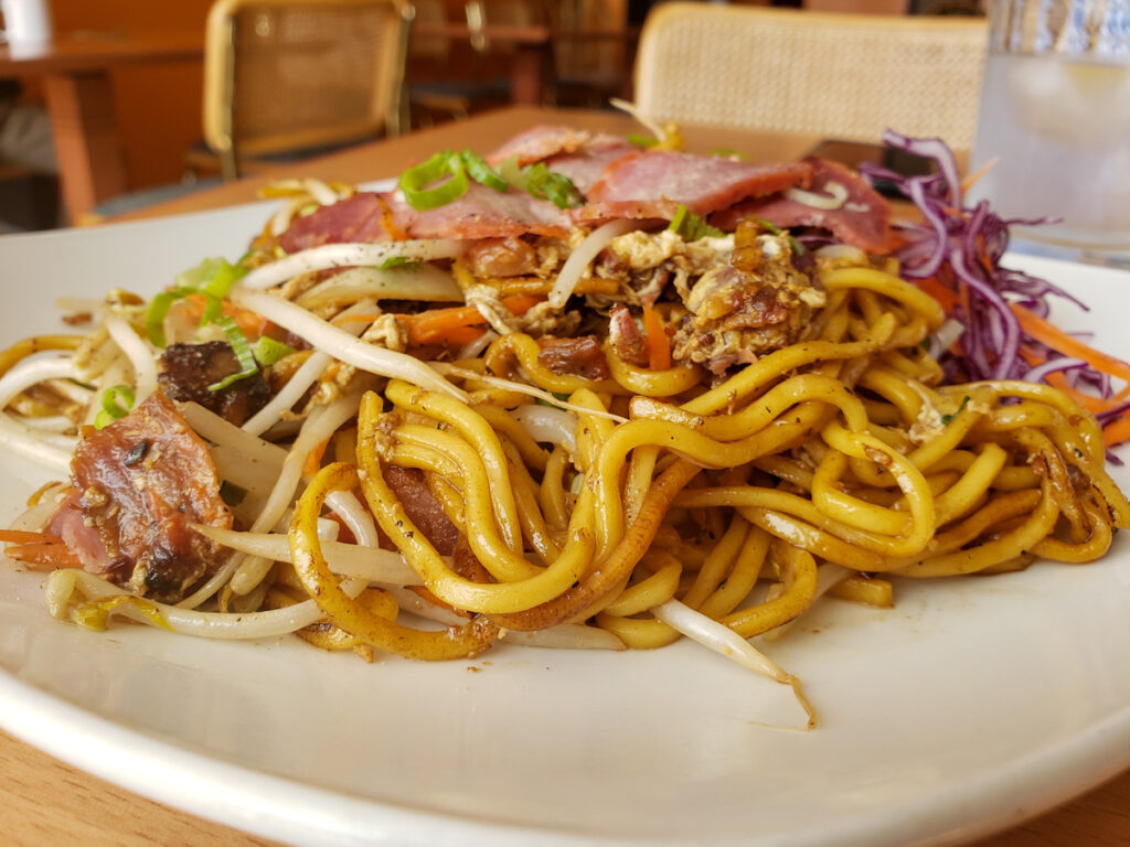 A plate of noodles with meat and vegetables.