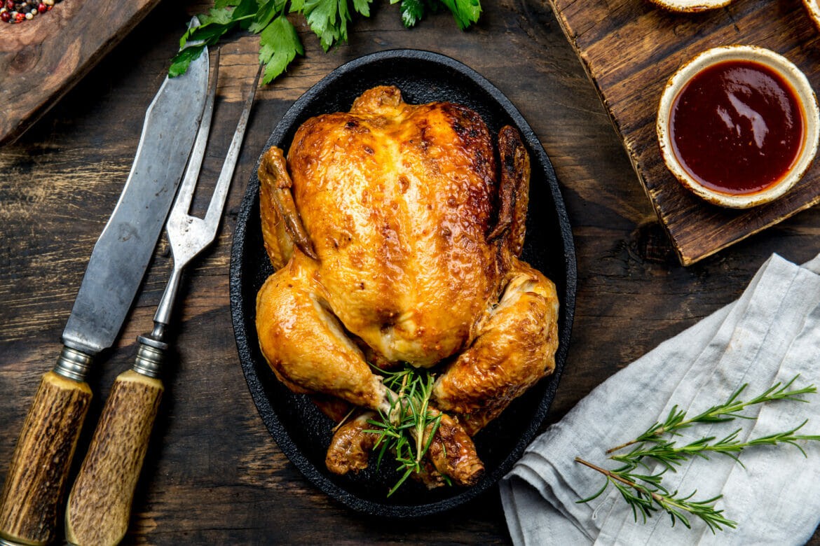 A herb roasted chicken is sitting in the middle of a pan.