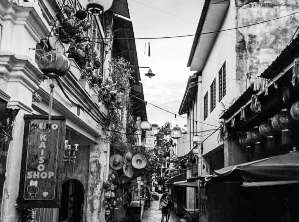 A black and white photo of an alley with people walking