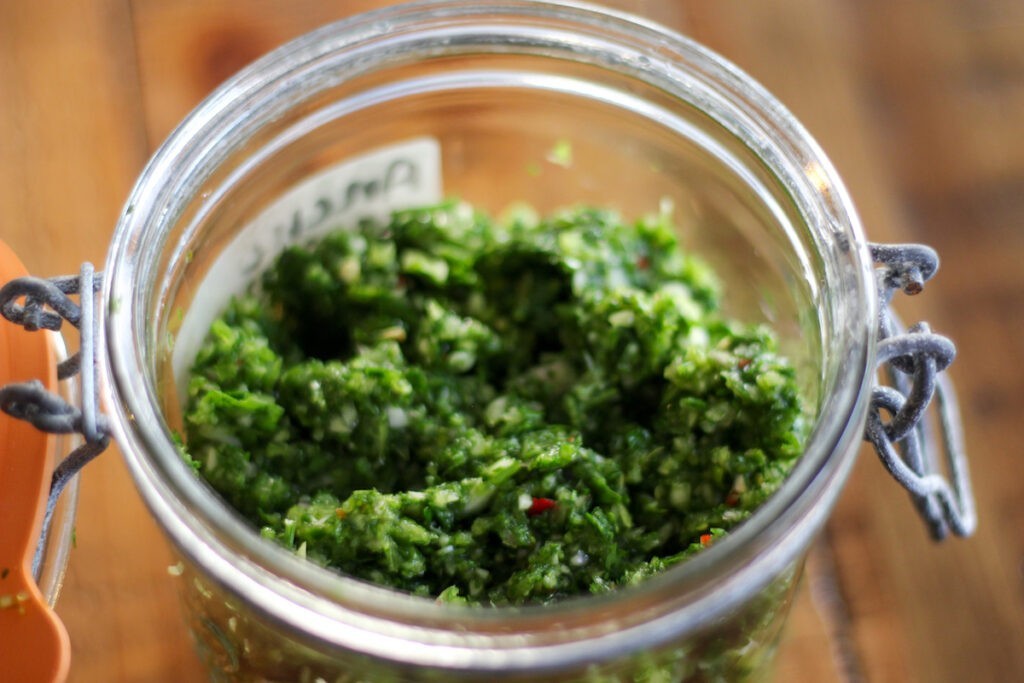 A jar of green stuff on top of a table.