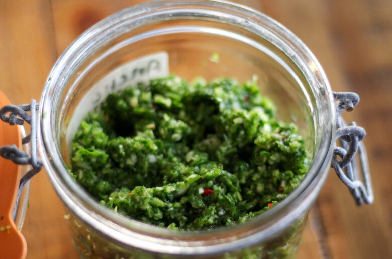 A jar of green stuff on top of a table.