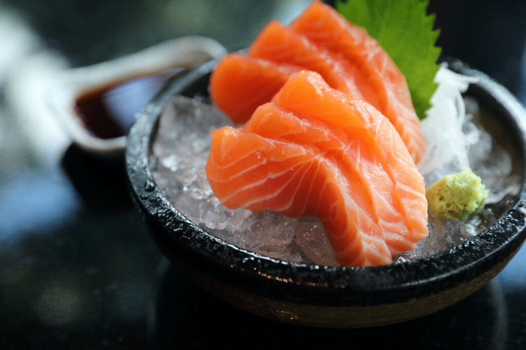 A plate of salmon on ice with sauce.