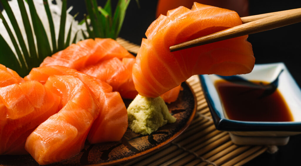 A person is holding chopsticks over some food.