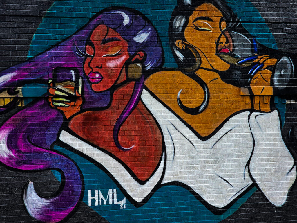 A mural of two women holding cell phones.
