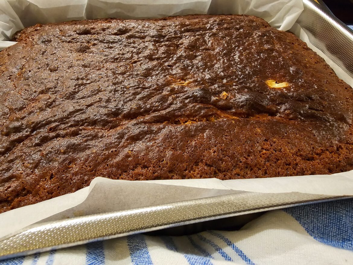 cake in pan with parchement paper and blue and white kitchen towel