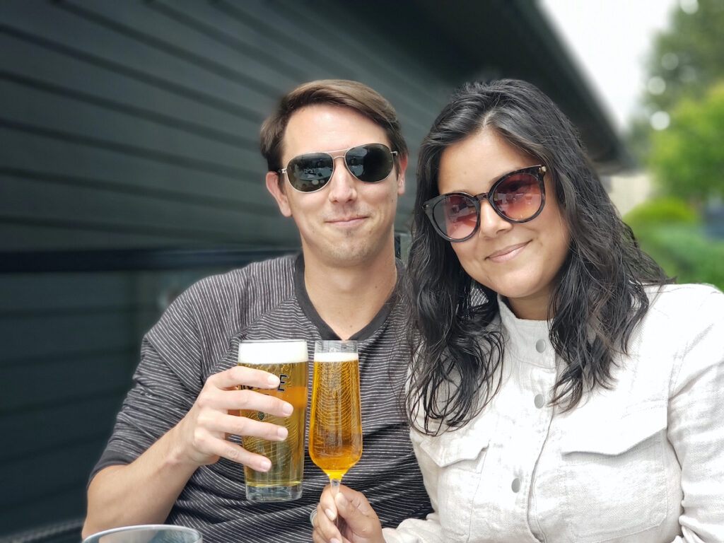 woman and man wearing sunglasses and touching beer glasses